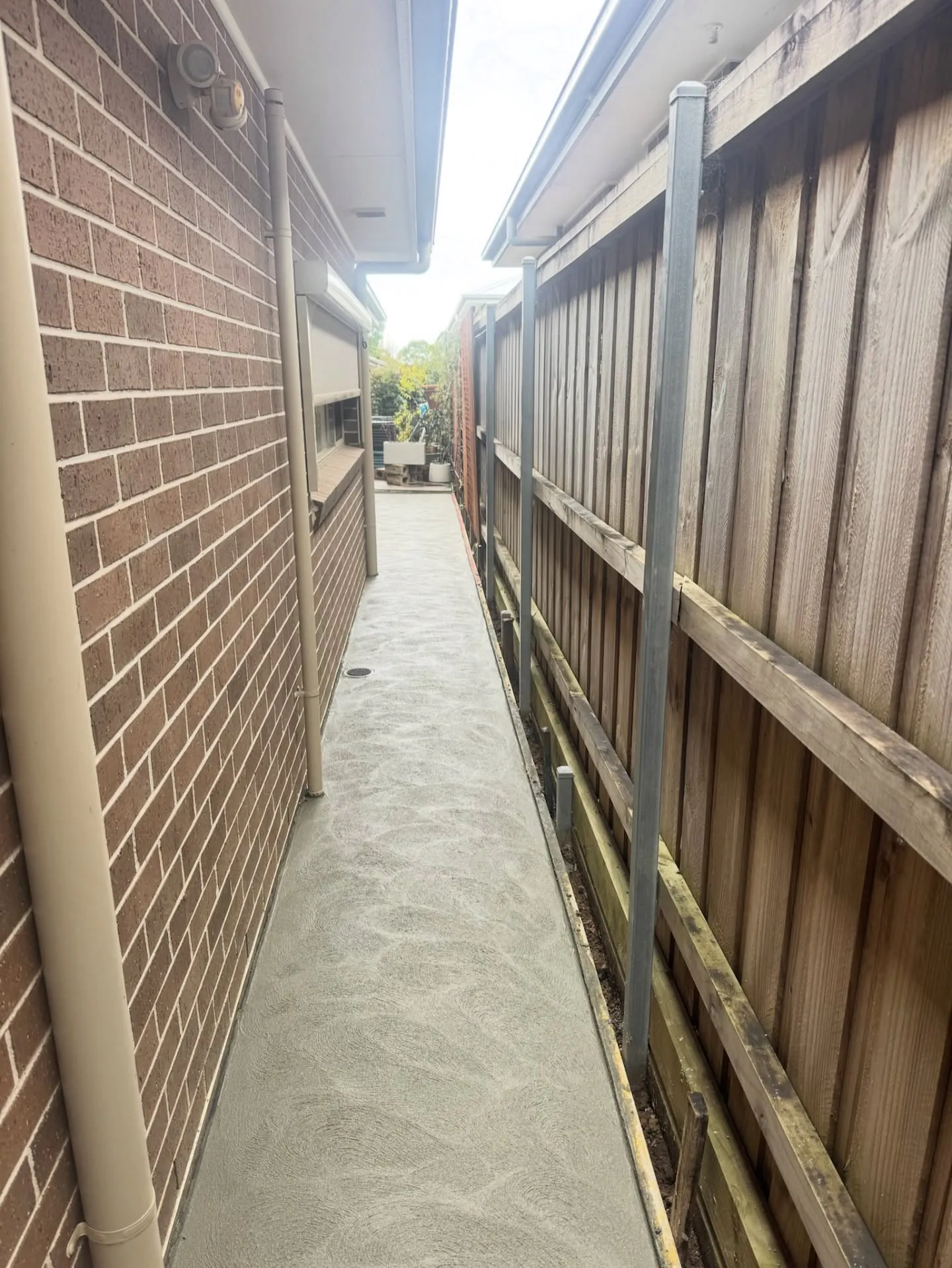 Concrete side access path between a house and a fence